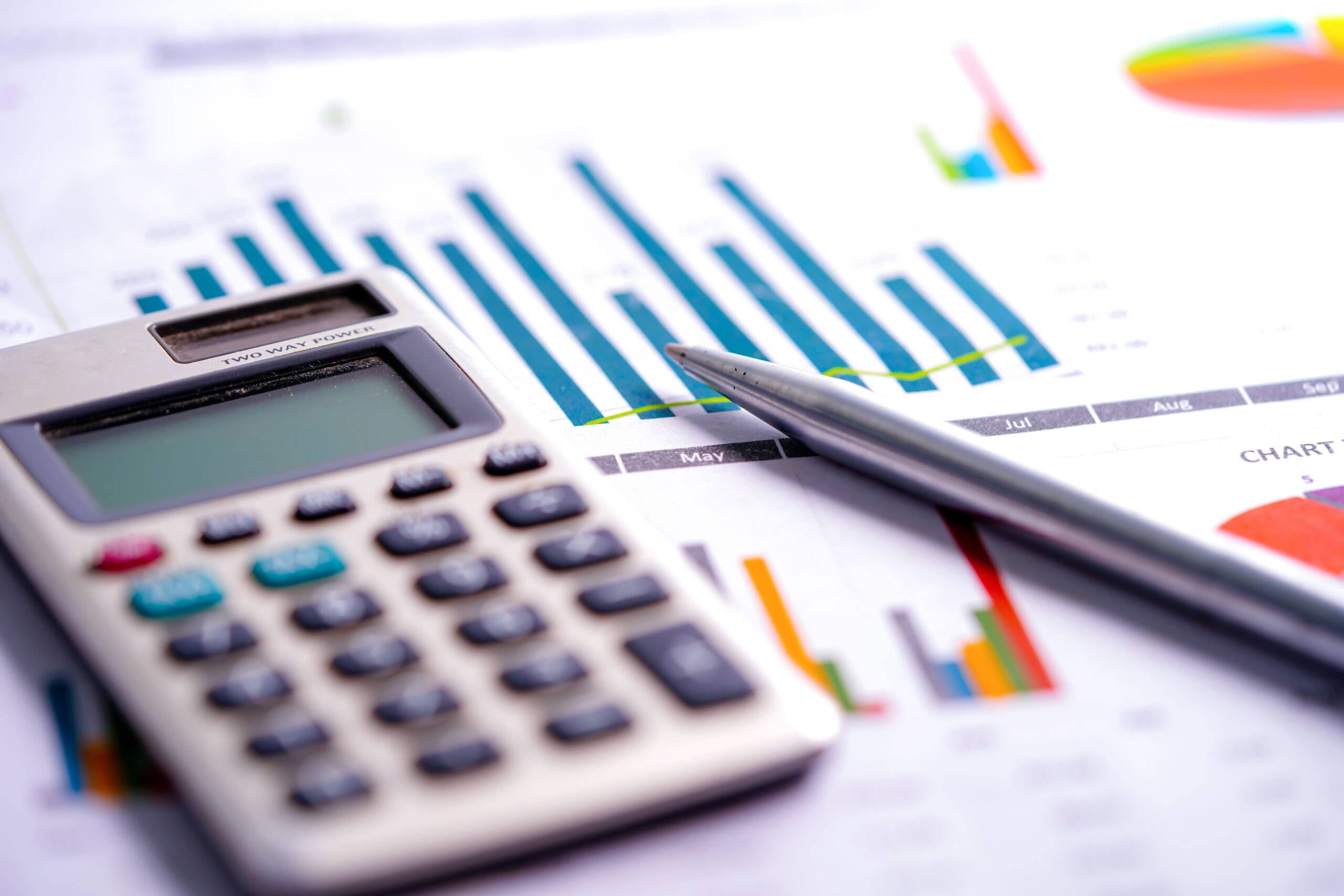 Calculator, pen, and financial charts for data analysis.