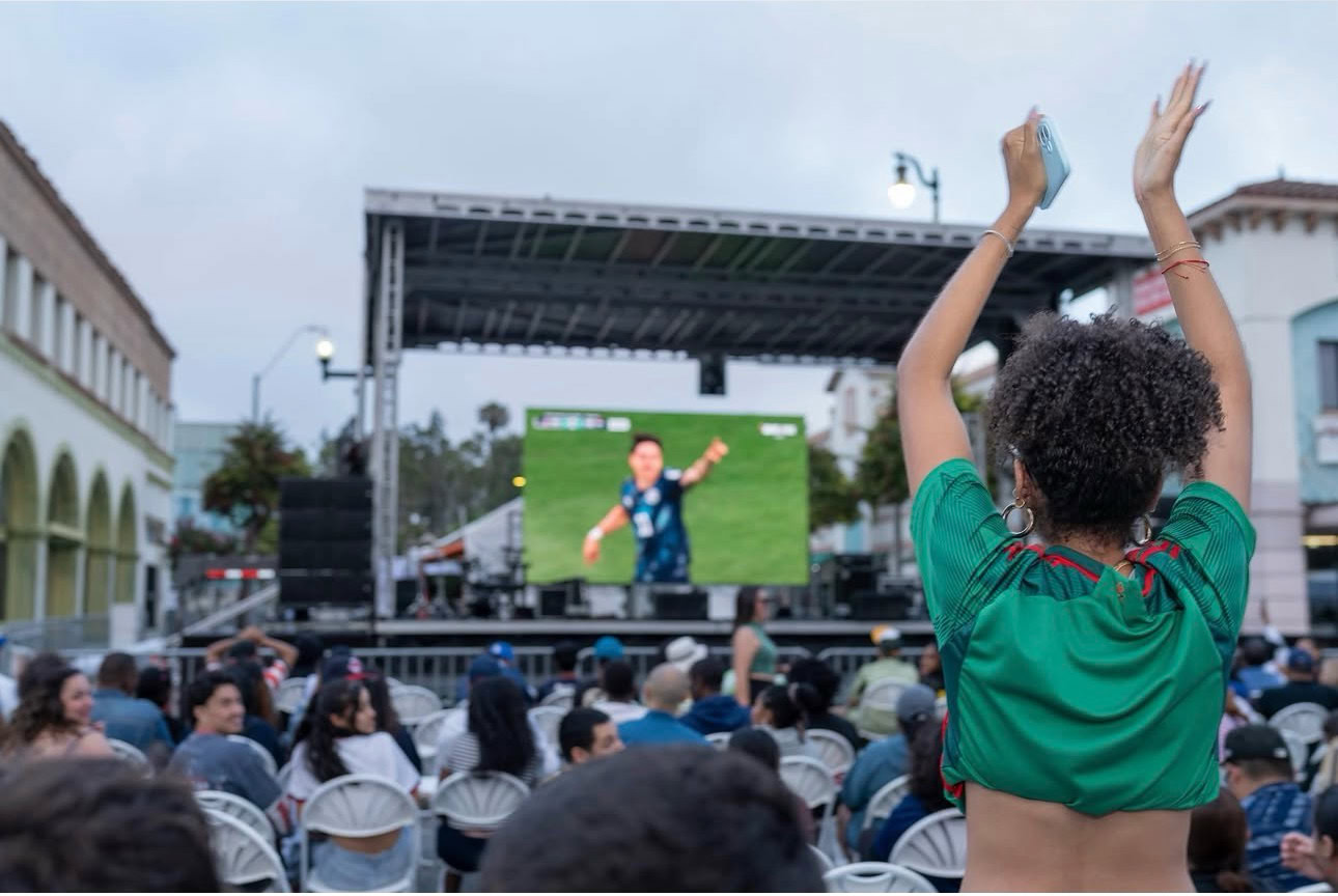 Children watching FIFA match on large outdoor screen at Kids Zone.