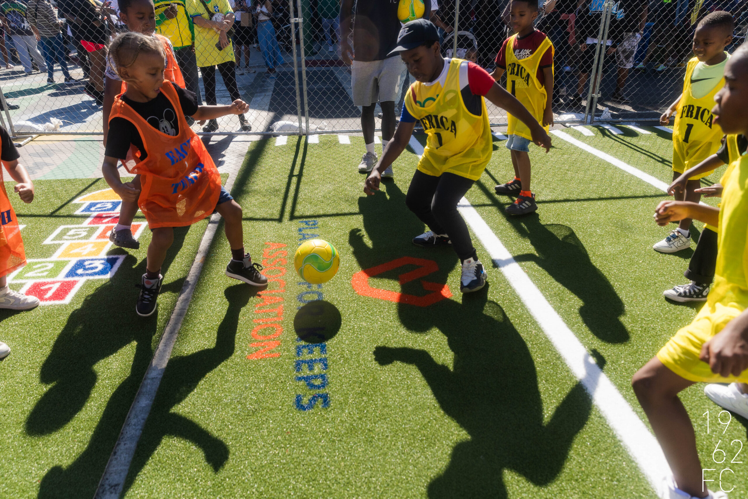 Children Playing Soccer on Artificial Turf Kids playing soccer on artificial turf with colorful jerseys and a ball.