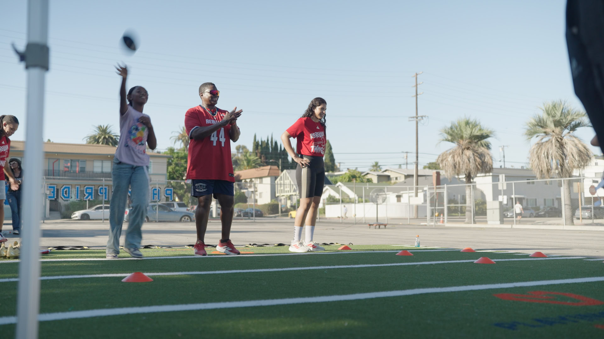 People Playing Football on a Field Group of people practicing football drills on a sports field outdoors.